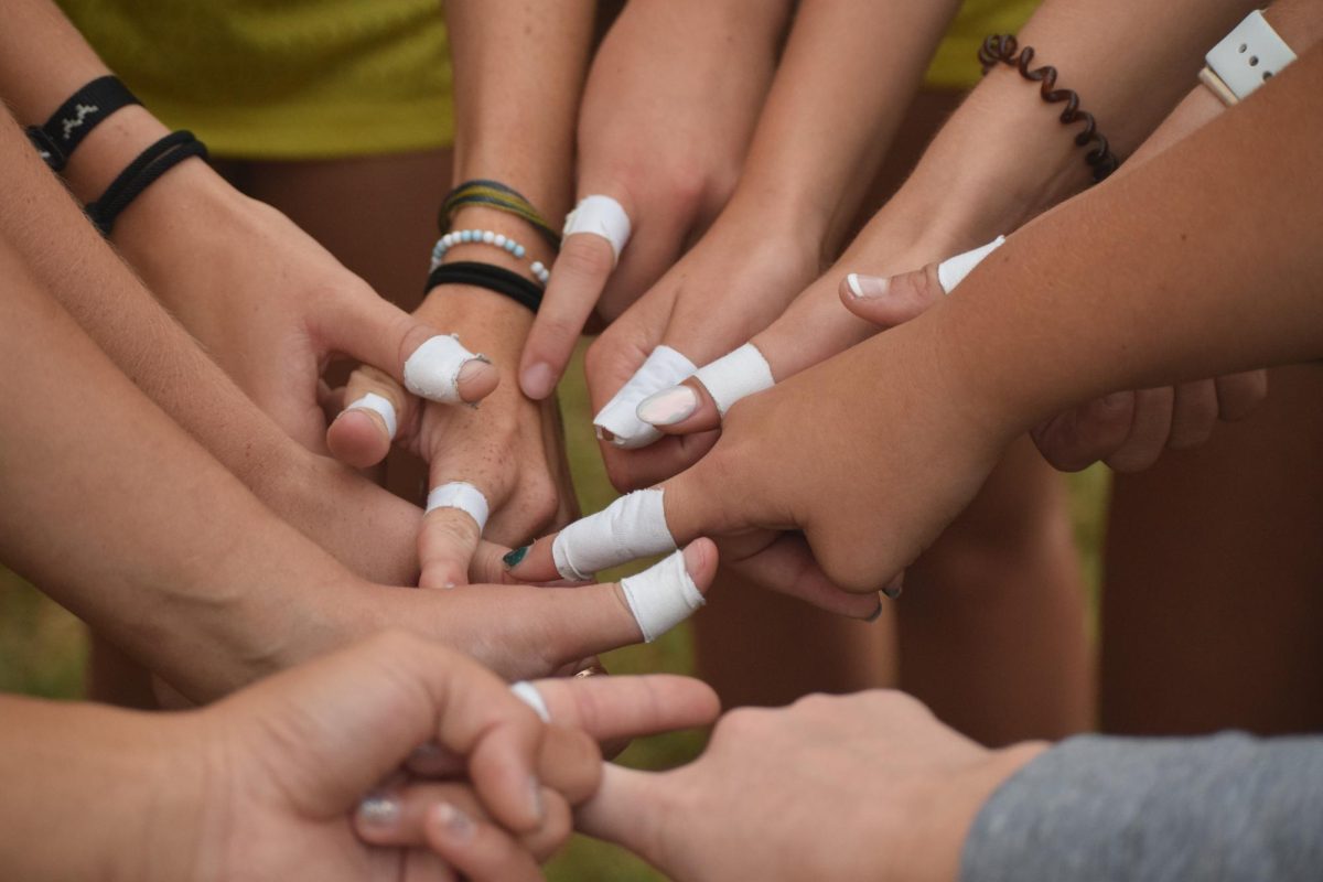 Girls XC runners put their thumb/ finger in fr a photo with the traditional white tape on their thumb/ finger.