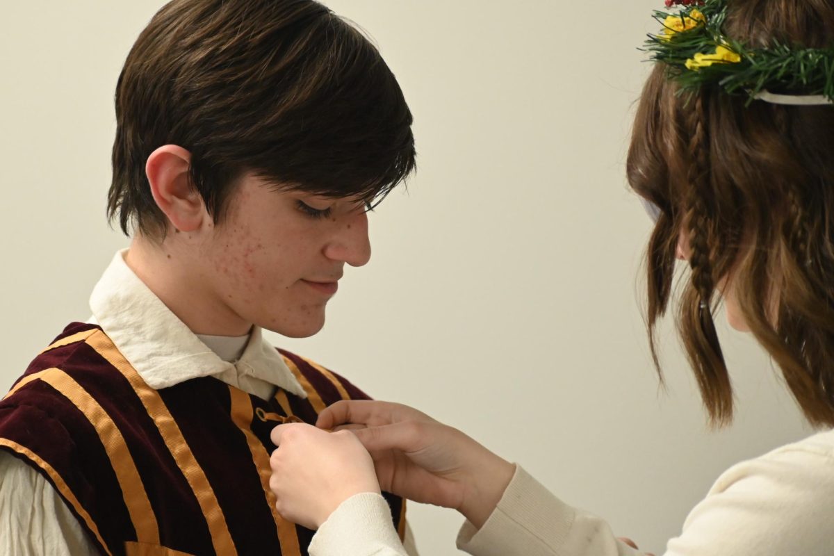 junior Makenna Alexander helps to fix junior Ethan Grime's tie at the 2022 Madrigals Dinner.