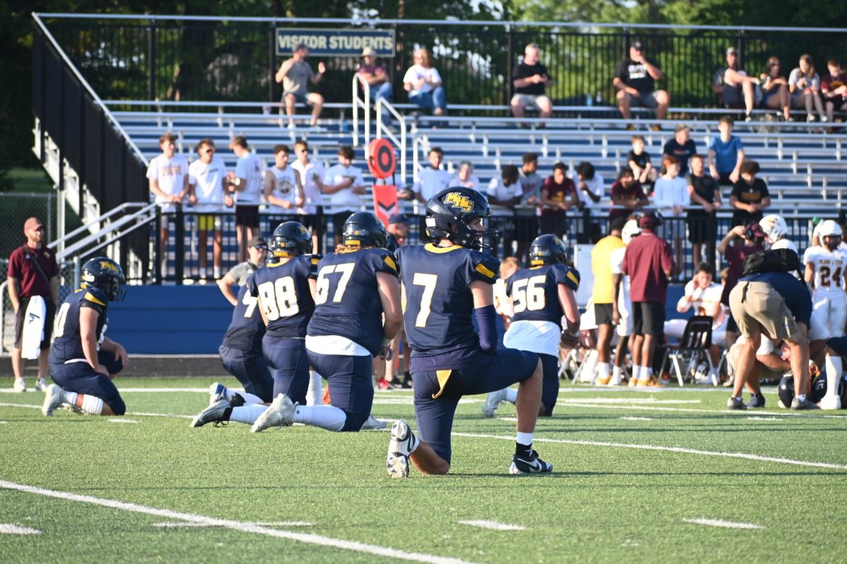  Senior Kaden Bruhn kneels for his teammate, number 51, senior Mason Mills. Bruhn waited patiently hoping for the best outcome. Even though the team lost Mills, they pushed through and brought the win home against Bloomington North.
