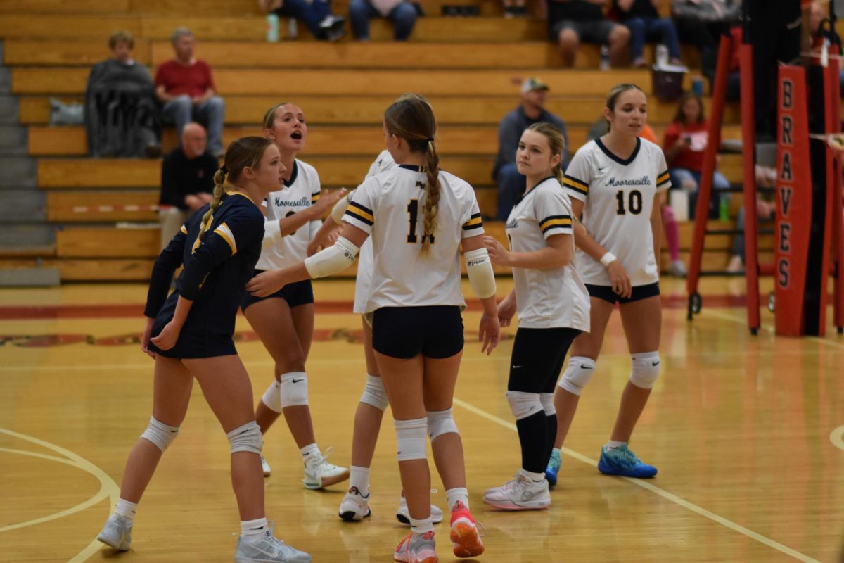 Junior Addison Gardner (#11) comes together with her team during a point to celebrate the team's success. Gardner scored for the JV Pioneers multiple times throughout the tough game. "I am glad I have the position that I do to help this team grow," Gardner said. 