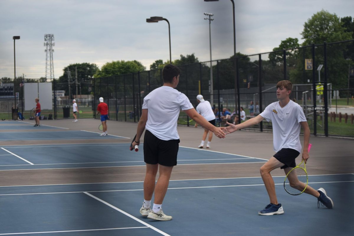 Junior Benjamin Coffey high fives his teammate Jared Kempf. They had just scored a point against Martinsville. "We usually high five after we score a point. It is like celebrating the victory of getting the point," Coffey said.