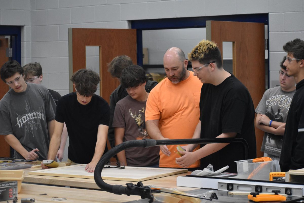 Students are shown the proper way to sand this board. Proper shelving and storage is something that the old building lacked, and the students are being allowed to be part of the process in the new building.