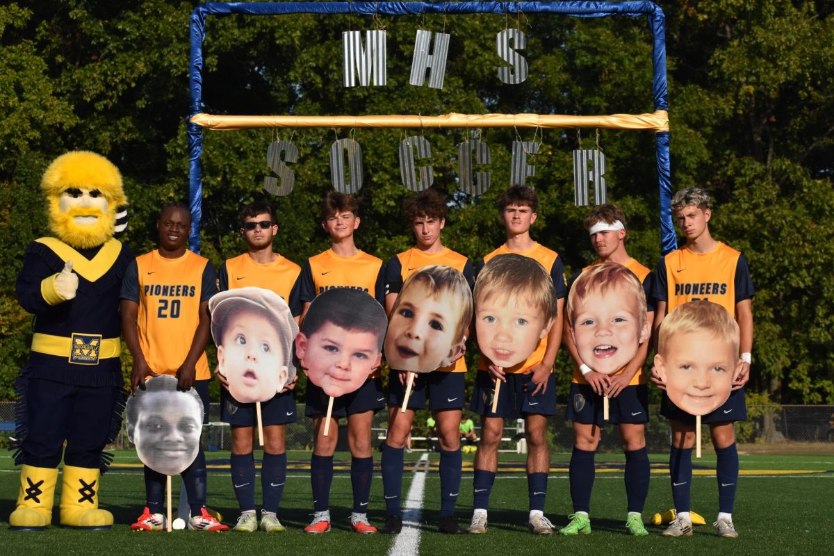 Boys soccer seniors pose with Pioneer Pete before their game.