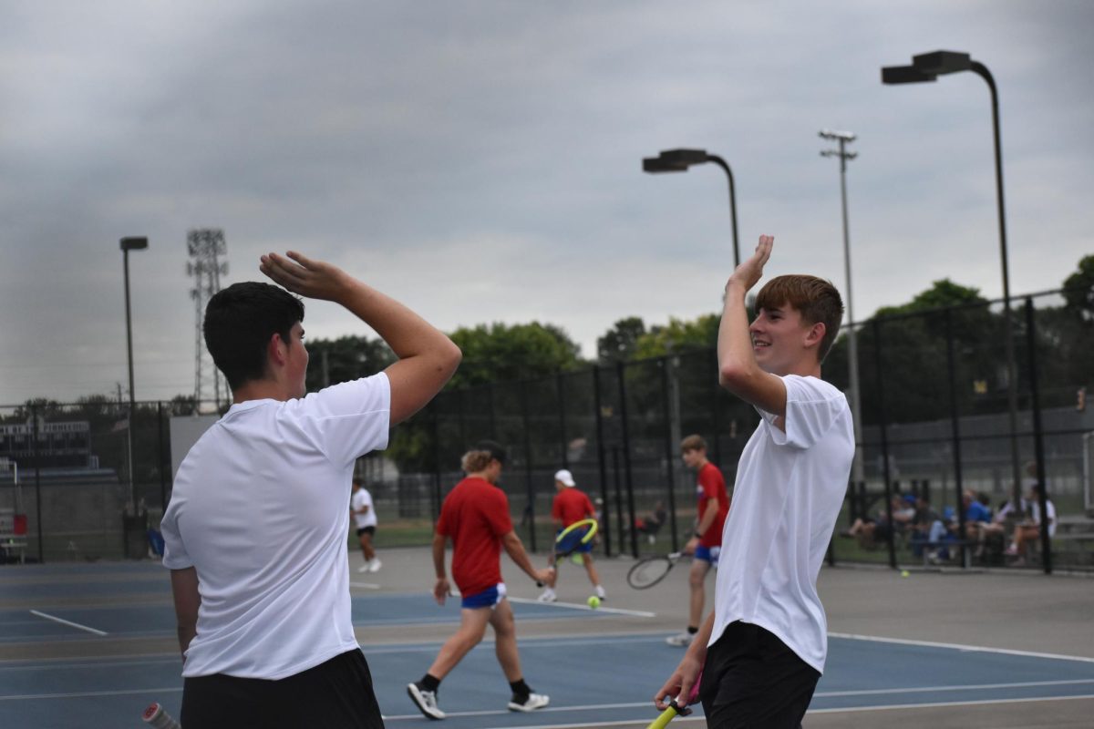 Senior Jared Kempf and Junior Ben Coffey share a high-five during their tennis match.