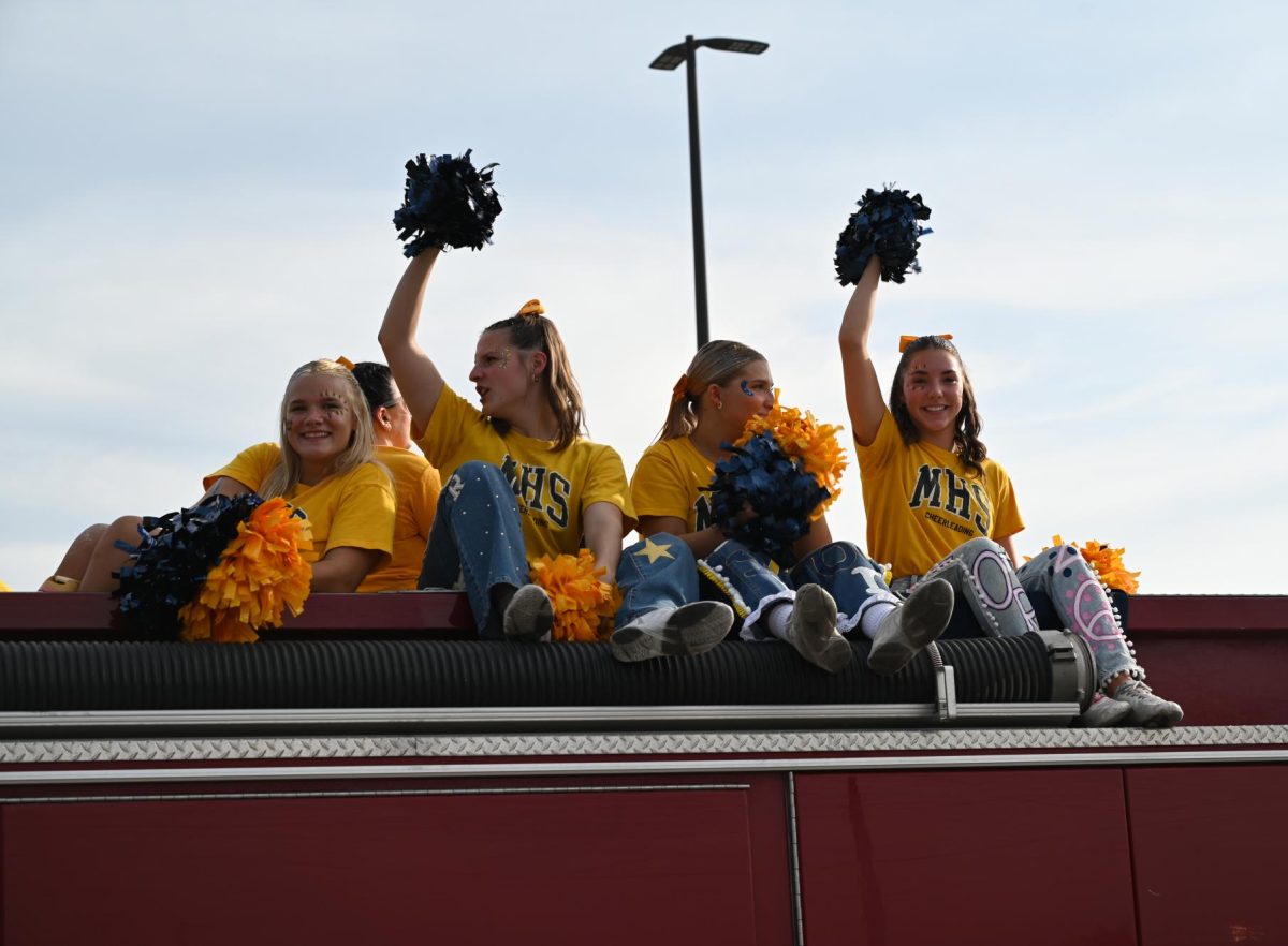 Mooresville's cheer team sits atop a firetruck in the Homecoming parade.
