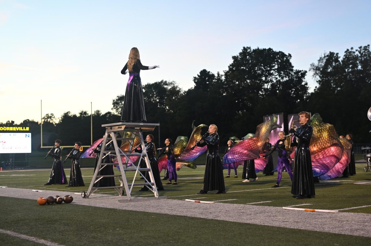 Both the band and color guard perform during a football game this season.